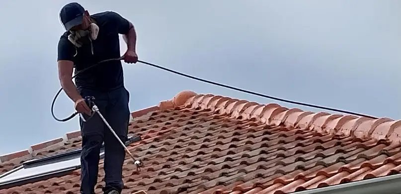 Davy Dedinger pulvérise un traitement sur une toiture en tuiles